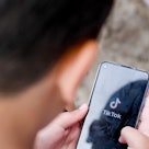 A child looking at a phone with the TikTok logo on it.