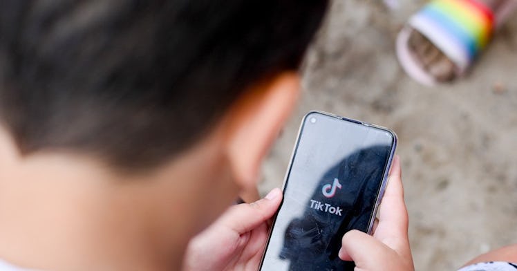 A child looking at a phone with the TikTok logo on it.