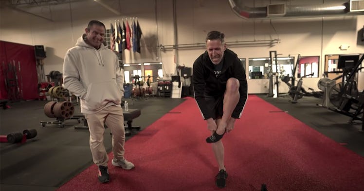 A man performs the old man test by balancing on one leg and putting on his shoe, while another man w...