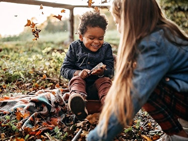 a boy and a girl play games outside together laughing and surrounded by signs of fall