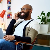 Man sitting in office talking on phone with big smile on his face