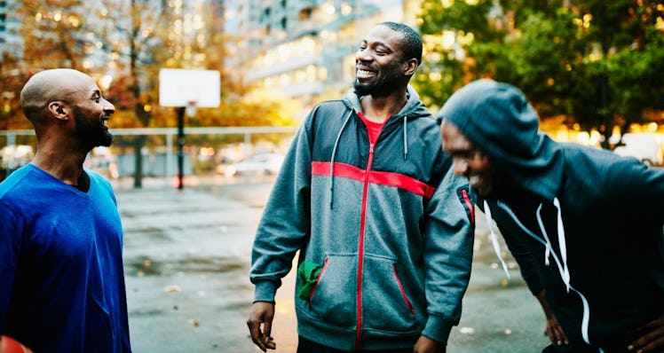 Three men on a basketball court laughing and smiling