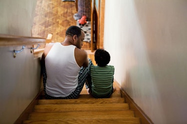 A dad talks to his son about ableist language while they sit on stairs.
