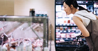 a woman looks at a chicken shelf in a store