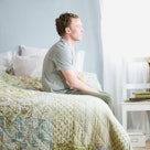 Man sitting up on edge of bed while wife sleeps