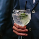 Man in suit holding a gin and tonic with cucumber