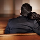 A mother and father sit in a pew in their funeral clothes.