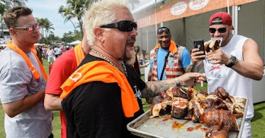 Guy Fieri hands out various meats to other men.