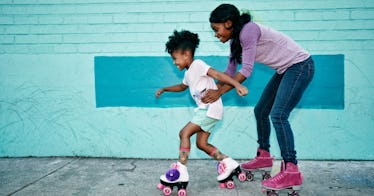 a kid and another kid rollerskate against a blue wall