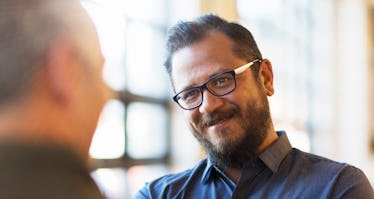 Man with glasses and beard listening to someone speak