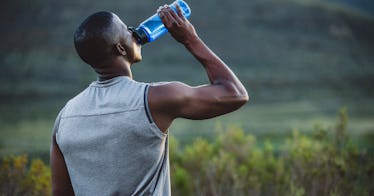 A man drinks water while taking a break from running outside.