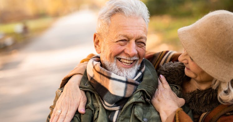 A woman has her arm around a man's shoulder as they laugh.