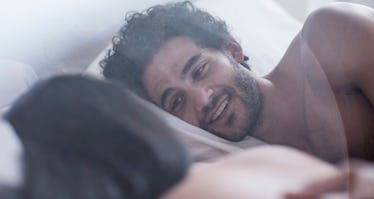 Couple laying on their sides and having a conversation in bed