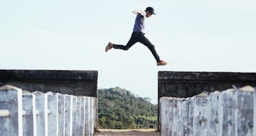 Man leaping over a gap to another wall