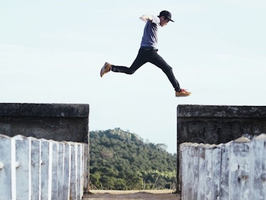 Man leaping over a gap to another wall