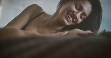 Woman smiling down at man as they lie in bed together