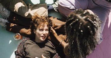 A teenager rest their head on their friend's lap as they sit beside two other friends.