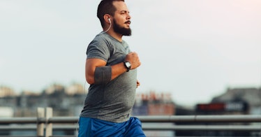 A man with a beer belly running in an urban area.