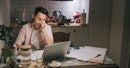 一个男人与脑雾在笔记本电脑在他的厨房里工作,看起来沮丧。