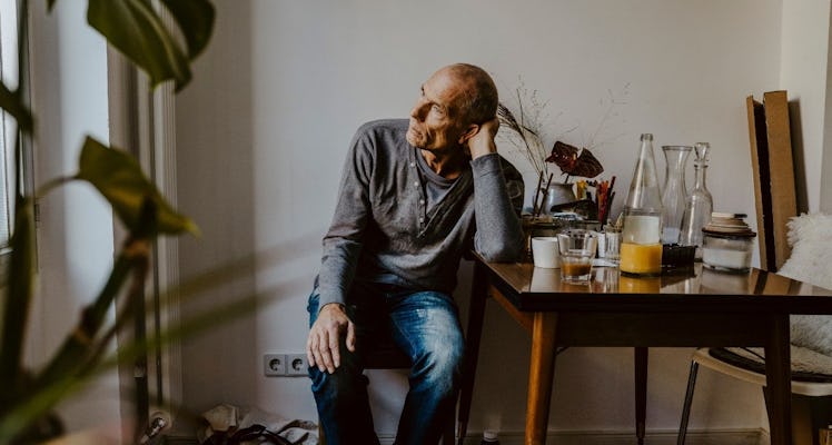 Worried man sitting at desk staring out the window.