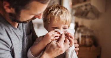 A father helps his child blow his nose.