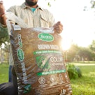 A man opening a bag of brown wood mulch