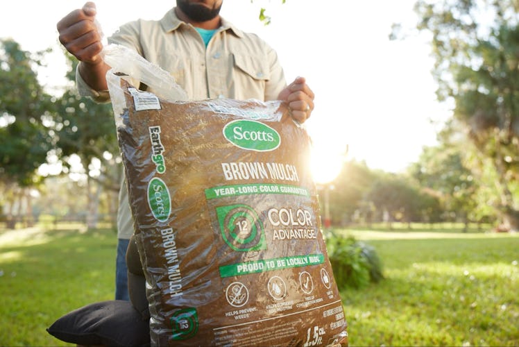 A man opening a bag of brown wood mulch