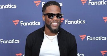 Kevin Hart in a black cardigan and white t-shirt, wearing sunglasses at a red carpet event