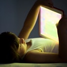 A child is on his iPad in the dark.