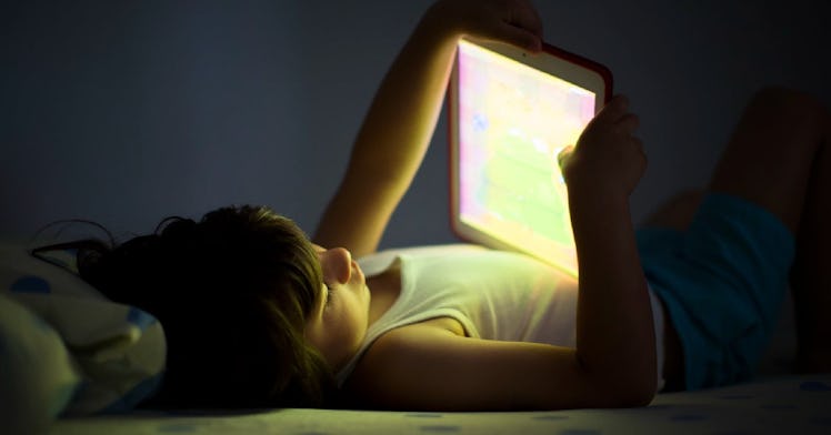 A child is on his iPad in the dark.