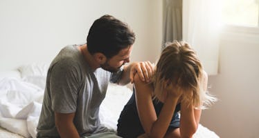 Man comforting upset wife on bed