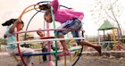 三个孩子在操场上玩一个快速跳跃的游戏结构。