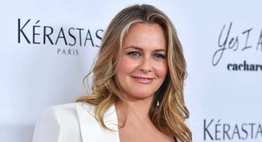 Alicia Silverstone at a red carpet, in a white blazer, sporting wavy hair. 