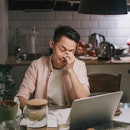 a guy sits, stressed out at his kitchen table looking over finances