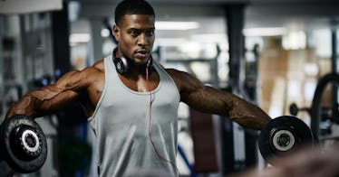 A muscular man lifts weights at the gym.