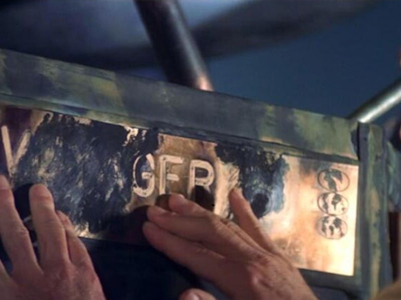 A man leaning his hands on a plaquette with the insignia 'VOYAGER'