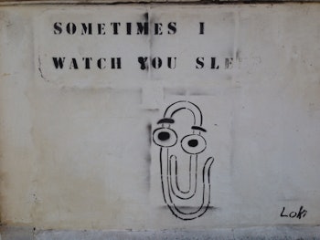 An illustration of Microsoft's Clippy character with a 'Sometimes I watch you' text