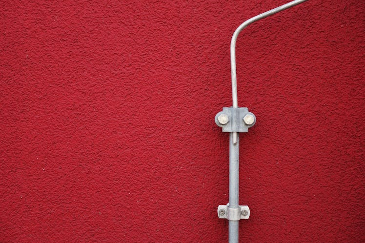 A wire construction shaped as a human face on a red wall 