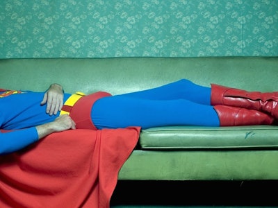 Christopher Reeve lying on a couch in a Superman costume
