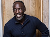 A portrait of Michael K. Williams smiling in a black shirt