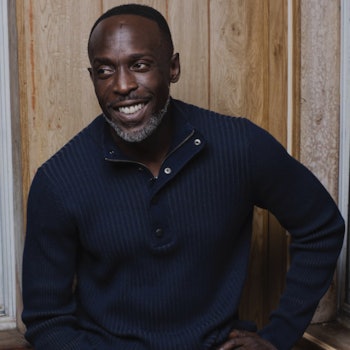 A portrait of Michael K. Williams smiling in a black shirt