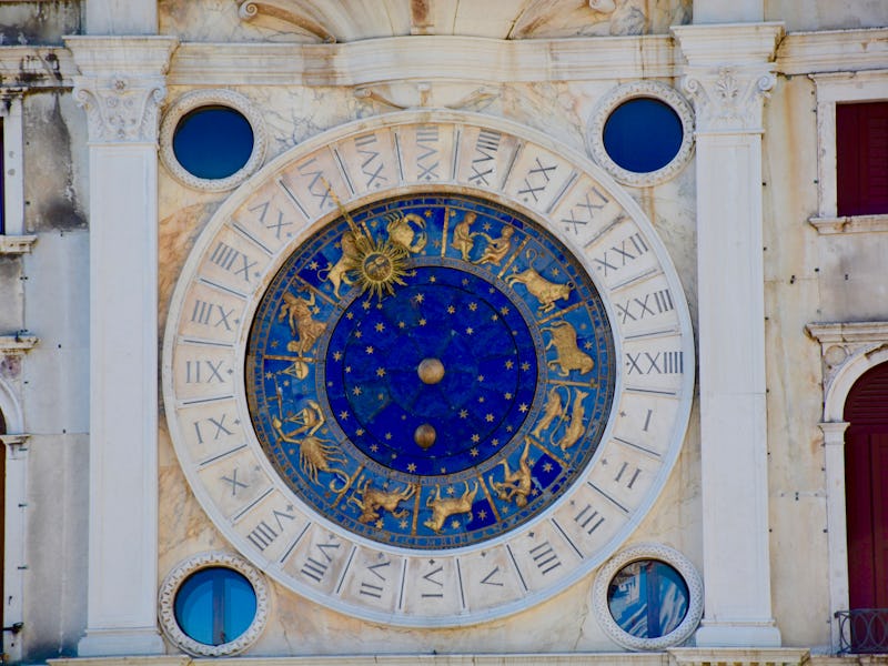 A blue zodiac wheel on the outer walls of an old building