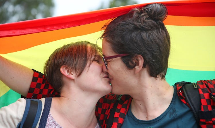 Alice Bennett and her partner Miranda Hill kiss as they gather with a crowd of people to watch a lar...