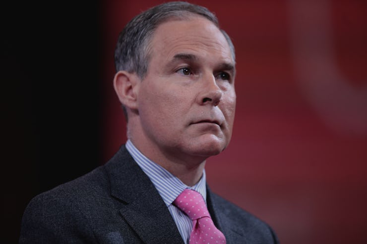 A close-up portrait of Scott Pruitt wearing a black suit, blue shirt, and red tie