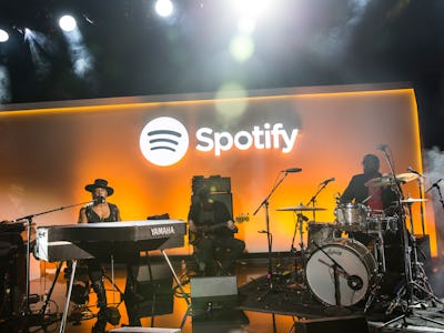 A band performing on a stage with the Spotify logo on a wall behind them