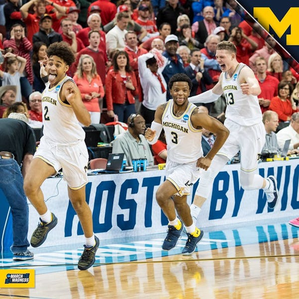 Three players from the Michigan basketball team celebrating a win on the court