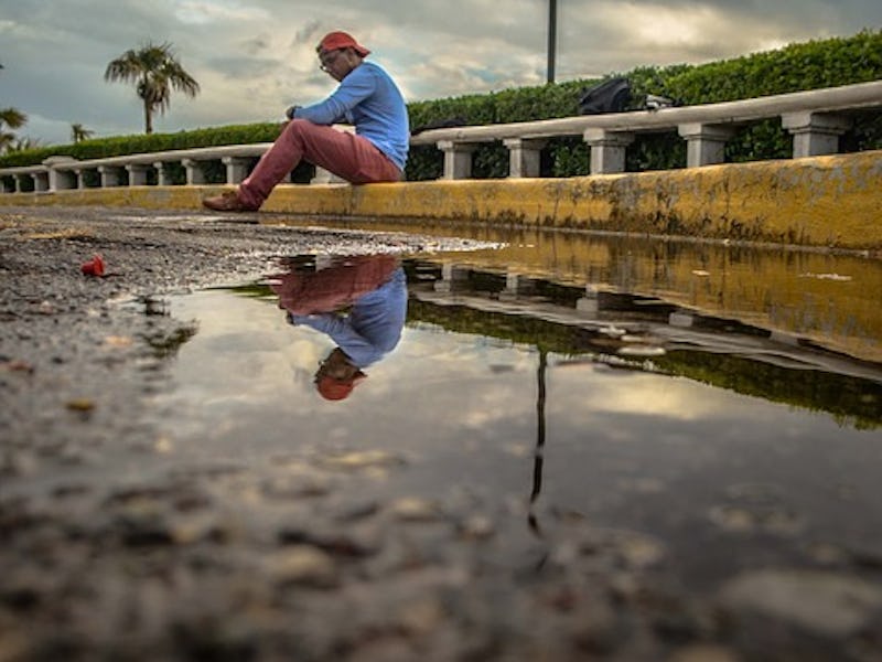 A man with a broken heart sitting alone on street concrete