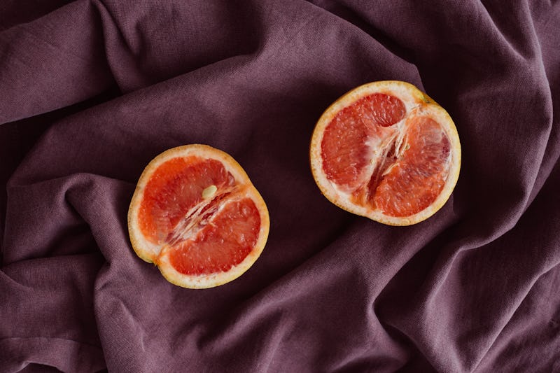 Grapefruit sliced in half and placed on a satin sheet.