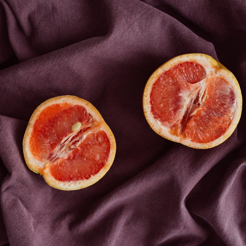 Grapefruit sliced in half and placed on a satin sheet.