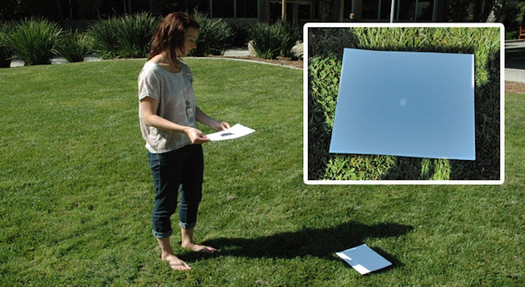 A woman putting a paper with foil on the grass